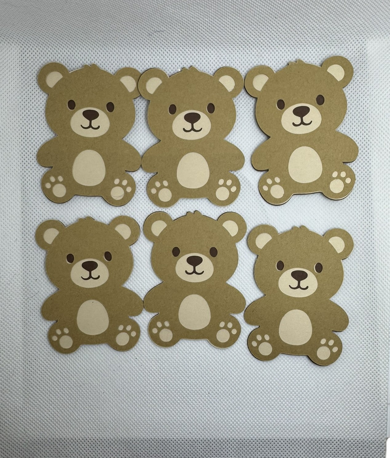 Set of six brown teddy bear cardstock die cuts arranged on a white background for baby shower decorations and paper crafts